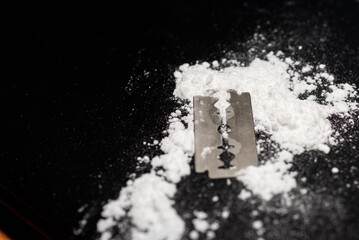 Razor Blade on drug powder on reflection black background.Copy space.