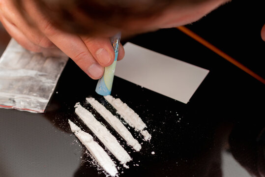 Drug addict. Drug abuse, man taking drugs, snorting lines of cocaine white powder, closeup.