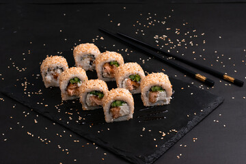 California roll maki sushi. Tasty fresh sushi rolls with salmon on black background. Japanese oriental cuisine