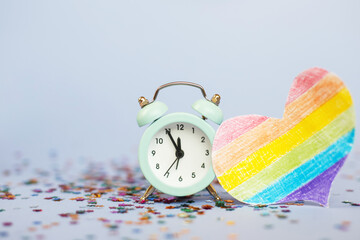 Alarm clock showing five minutes to twelve with milticolored sequins and lgtb flag in the form of a...