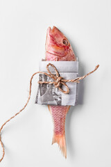 Salt-dried red mullet wrapped in newspaper and tied with thread on white background