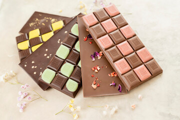 Multicolored fruit chocolate bars on black background. Handmade chocolate with mint, mango, orange, strawberry flavor. Healthy food concept, delicious chocolate sweets for kids, diet, sugar