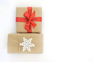 Christmas and New Years flatlay background. Gift box wrapped in kraft paper with jute cord. Decorated with a crocheted snowflake. Box with a red ribbon. Place for your text