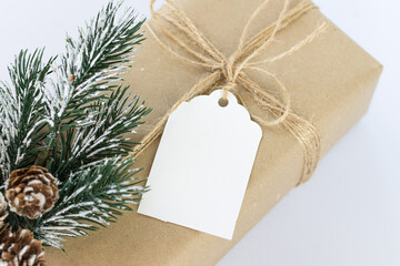 Christmas and New Years background close-up. Gift box wrapped in kraft paper with jute cord. Decorated with a label and a branch with cones