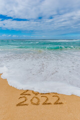 2021 2022 written in the sand with a wave washing away 2021- New Year’s concept