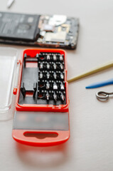 Disassembled Smartphone, hand tools and parts on a light surface