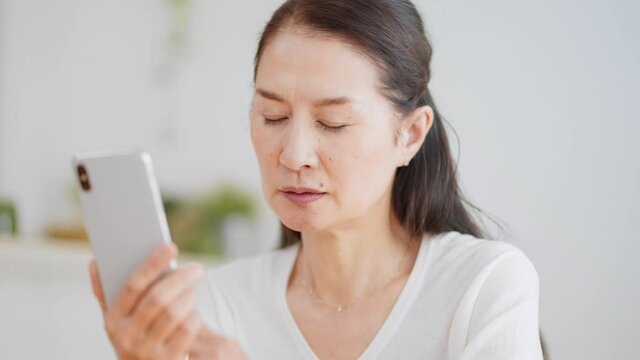 スマートフォンを見る眼精疲労のシニア女性