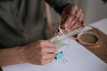 woman fixes glass plates. A picture of dried flowers. Master class on creating frame. be more...