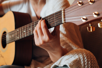 Musical hobby, learn music concept. Close-up of woman playing an acoustic guitar, indoors....