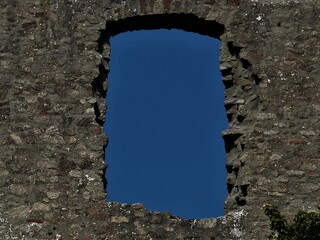Steinmauer mit Fensteröffnung und blauer Himmel im Hintergrund