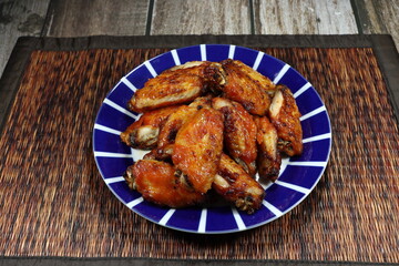 Pile of grilled chicken wing serving on the plate. Famous appetizer menu in Asian restaurant. 