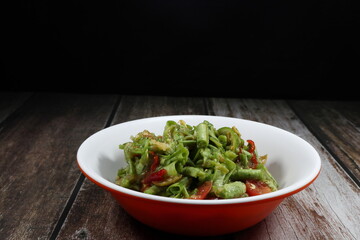 Traditional spicy string bean salad (Green Yard long bean) dressing with pickled fish sauce serving in the bowl. Famous local street food menu in Asia.