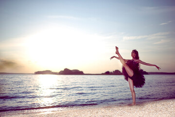 Fototapeta na wymiar Professional Sensual Japanese Ballet Dancer in Black Tutu And Silver Crown Posing Near Seashore During Ballet Pas in Summertime in Dance Pose Outdoor.
