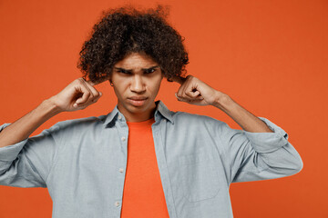 Young student black man 50s wearing blue shirt t-shirt cover ears with hands fingers do not want to listen scream isolated on plain orange color background studio portrait. People lifestyle concept.