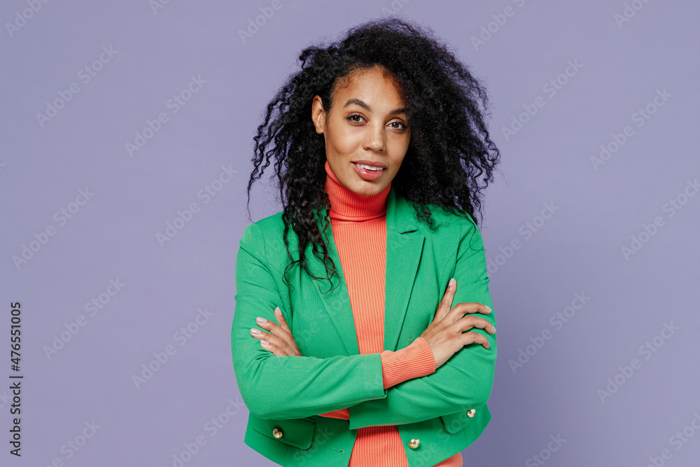 Wall mural Vivid swanky young black curly woman 20s years old wears green shirt look camera hold hands crossed isolated on plain pastel light violet background studio portrait. People emotions lifestyle concept.