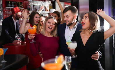 Happy young man with female friends enjoying cocktail party in bar