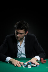 Concentrated Handsome Caucasian Brunet Young Pocker Player At Pocker Table With Chips And Cards While Drinking Alcohol.