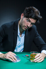 Concentrated Handsome Caucasian Brunet  Pocker Player At Pocker Table With Chips While Dealing Cards and Drinking Alcohol.