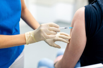 Schutzimpfung mit Spritze in den Oberarm eines Mannes.