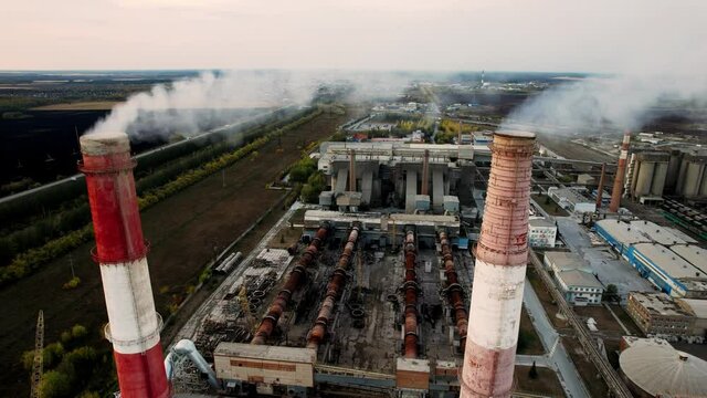 Drone around toxic enterprise chimneys tubing against the sky background release smoke. Industrial factory pollution, smokestack exhaust gases. Industry zone, thick smoke plumes. Climate change, ecolo