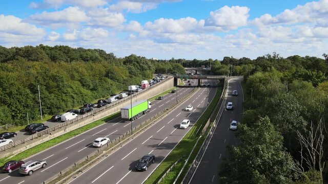 traffic on highway on sunny day. Revealing panoramic view of wooded landscape at suburb. Woodford, London, UK.