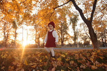 a small child in a white sweater and a red knitted hat comes down the hill 