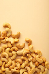 Cashew nuts on beige background. Top view. Vertical photo