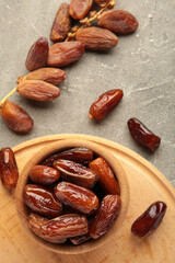 Wooden bowl of dried dates on grey wooden background. Vertical photo.