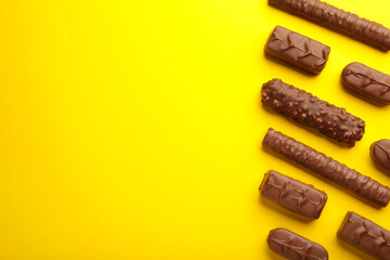 Mix of chocolate bars on yellow background. Top view.