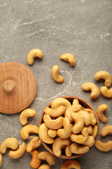 Cashew nuts on wooden bowl on grey background. Top view.