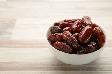 White bowl of dried dates on grey background.