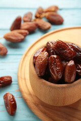 Wooden bowl of dried dates on blue wooden background. Vertical photo.