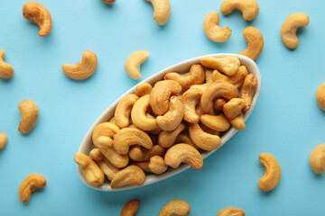 Cashew nuts on white plate on blue background. Top view.