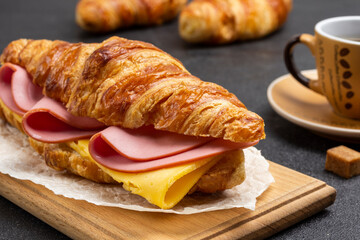Croissant with ham and cheese on board.