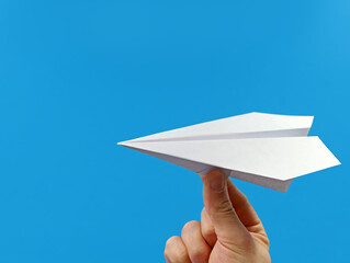 male hand holding paper plane isolated on blue background with copy space
