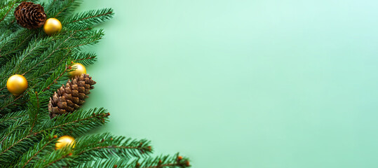 Christmas flat lay: fir branches with cones and golden balls on green background, banner, copy space