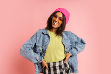 Stylish  fancy african woman in pink hat , cool sunglasses and  jeans jacket posing on pink...