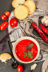 Vegan food, spicy tomato gazpacho soup with toasts, ripe vegetables, and fresh basil herbs