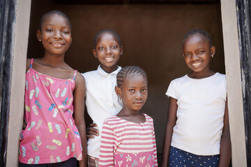 Group of four cool black African girls in casual clothes smiling at the camera and showing a...