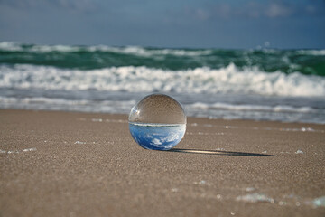 Fototapeta na wymiar Glass globe on the beach of the Baltic Sea in Zingst in which the landscape is depicted.