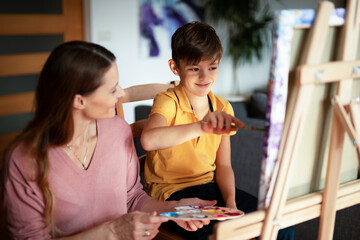 Obraz premium Mother and son painting at home. Little boy drawing with mom in living room