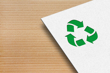 Recycle symbol with white paper on a cardboard background