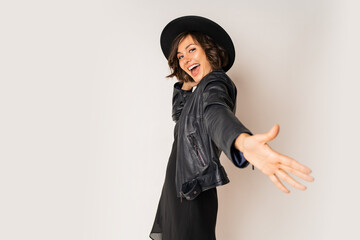 Party mood. Laughing woman  in black hat, evening dress and leather jacket  having fun and dancing...