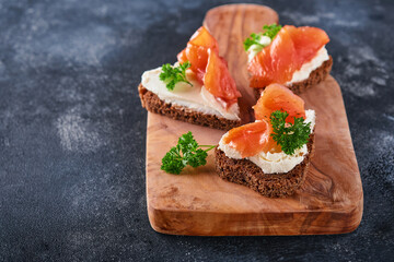 Mini sandwiches with salmon, curd cheese, parsley and rye bread in form of hearts. Valentine's day...