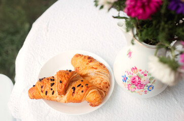 Croissants on a plate in a summer garden or on a terrace in a cafe.