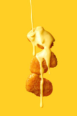 Levitating chicken nuggets topped with cheese sauce. Flying nuggets with flying sauce. Yellow...