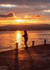 fisherman fishing on Bosporus İstanbul on a Foggy sunrise. Fishing rods on seaside. People jogging on coast. people walking in morning