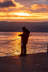 fisherman fishing on Bosporus İstanbul on a Foggy sunrise. Fishing rods on seaside. People jogging...