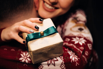 Close up of young beautiful woman hugging man holding Christmas present. Family tradition. Exchange of gifts. Christmas holidays celebration concept.