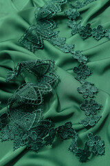 Vertical image of green lace on the soft silk as background.Fresh spring deep color